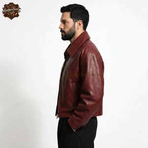 May include: A burgundy leather jacket with a collared neckline and a front zipper closure. The jacket has a classic design with a tailored fit. The Leather Soul Crafts logo is visible on the upper left corner of the image.