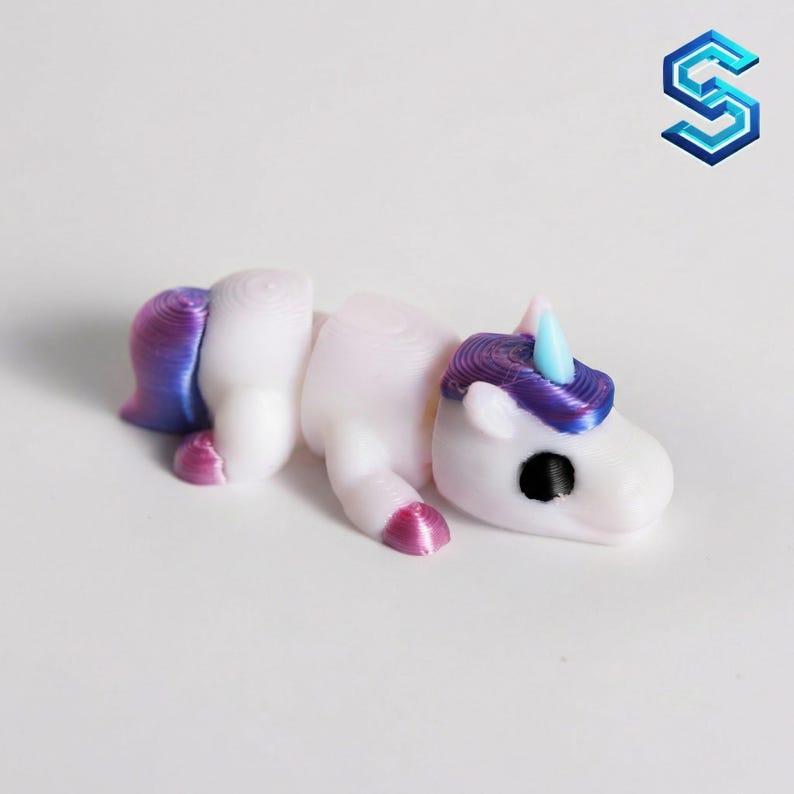 May include: A small, articulated unicorn figurine featuring a white body with a purple mane and tail, and a light blue horn. The figure has a smooth, layered texture typical of 3D printing, with a black eye and pink accents on the hooves.