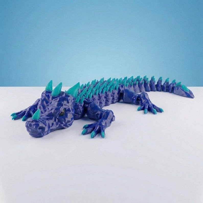 May include: A dark blue articulated lizard figurine featuring a textured, scaly surface and bright teal spikes running along its back, head, and tail. The creature has four legs with clawed feet and a pointed snout, with teal accents on the claws.