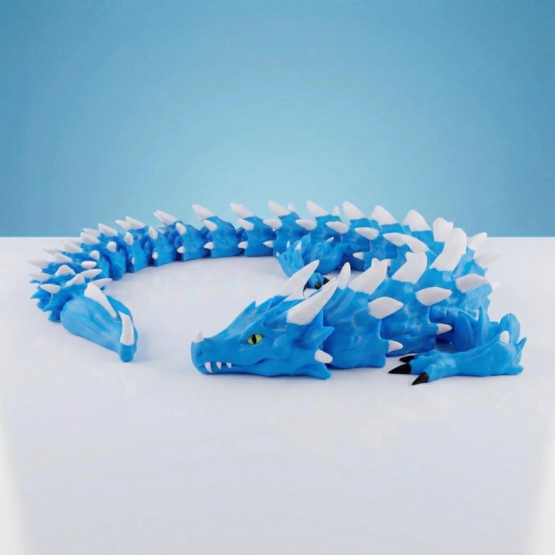 May include: A blue articulated dragon figurine featuring a long, segmented body with white spikes along its back and tail. The dragon has a detailed head with yellow eyes, white horns, and sharp white teeth, with black claws on its front limbs.