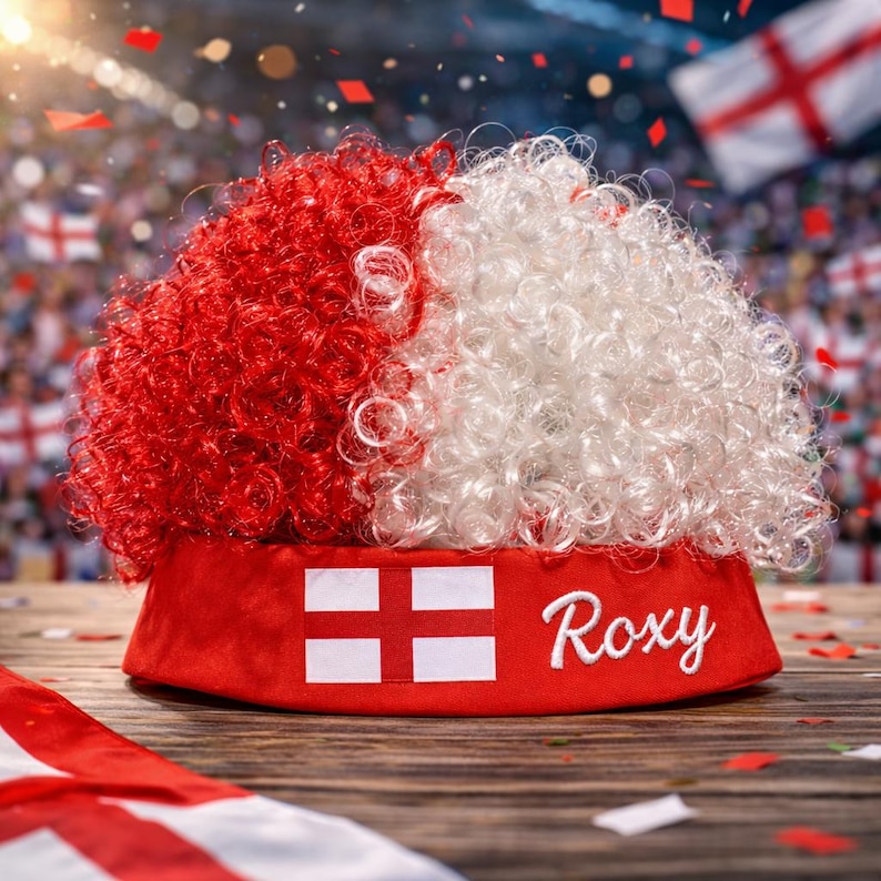 Peut inclure: Perruque boucl&eacute;e rouge et blanche sur un chapeau rouge avec le texte "Roxy" et le drapeau anglais. La perruque est divis&eacute;e en sections rouges et blanches. Le chapeau porte le drapeau anglais.