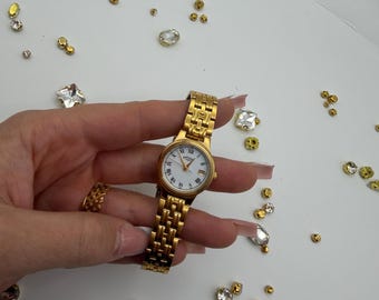 Reloj de pulsera vintage Rotary para mujer, tono dorado, con esfera de números romanos y ventana de fecha.