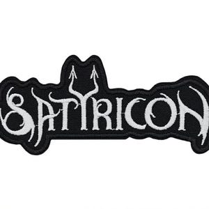 Könnte beinhalten: Ein schwarzer bestickter Aufnäher mit dem Wort SATYRICON in weißer, stilisierter Schrift. Der Text hat eine markante, gezackte Schriftart mit einem nach oben gerichteten Pfeildesign, das in den Buchstaben Y integriert ist.