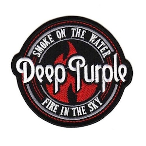 May include: A circular embroidered patch featuring a black background with a central red flame graphic. The text Deep Purple is stitched in white across the center, with Smoke On The Water and Fire In The Sky embroidered in white along the border.