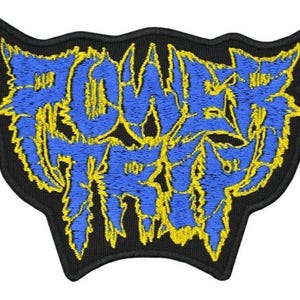 May include: An embroidered patch featuring the text POWER TRIP in a jagged, stylized blue font with a bright yellow outline. The design is set against a black background with a thick black border, creating a sharp contrast between the colors.