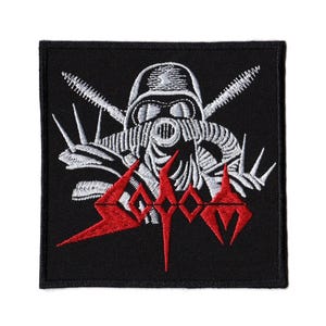 Op de afbeelding: Zwart vierkantige patch met een wit en rood geborduurd ontwerp. Het ontwerp toont een gasmasker, gekruiste zaagbladen en het woord "Sodom" in rode, gestileerde letters. De patch is waarschijnlijk voor een jas of tas.