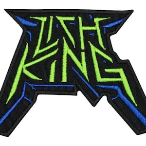 May include: Black embroidered patch with the text "ISH KING" in neon green and blue. The patch has a jagged, angular design, with the letters outlined in blue and filled with green.
