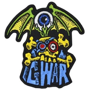 Puede incluir: Parche bordado con un diseño estilizado que presenta un ojo grande, alas y la palabra "GWAR" en letras azules. El parche tiene un fondo negro con detalles en amarillo, verde, azul y rojo. El diseño es detallado y audaz.