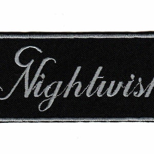 Può includere: Una toppa rettangolare ricamata con sfondo nero e bordo grigio argento. La parola Nightwish è cucita al centro con un carattere corsivo grigio argento. La toppa presenta un bordo rifinito e una consistenza piatta e tessuta.