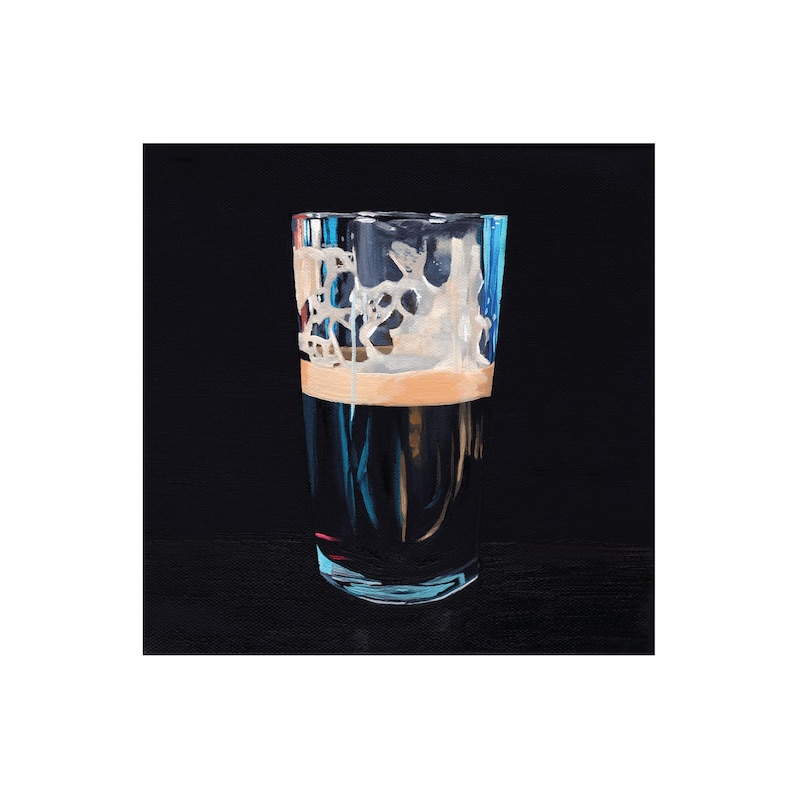 May include: A tall glass filled with a dark liquid, topped with a creamy, off-white foam. The glass has a clear, slightly blue tint, and the background is a solid black. The image is a close-up of the glass, highlighting the texture of the foam.