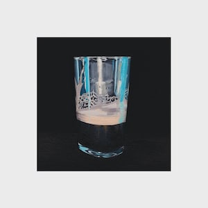 K&ouml;nnte beinhalten: Ein klares Glas mit einer gemalten Winterszene. Das Kunstwerk zeigt eine verschneite Landschaft mit blauen und wei&szlig;en B&auml;umen und einem hellen Himmel. Das Glas hat einen dunklen Boden und einen gebogenen Boden.