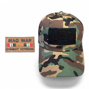 May include: Camouflage baseball cap with a black patch and an Iraq War Combat Veteran patch. The cap features a woodland camouflage pattern in shades of green, brown, and tan. The patch is rectangular with text and a ribbon design.