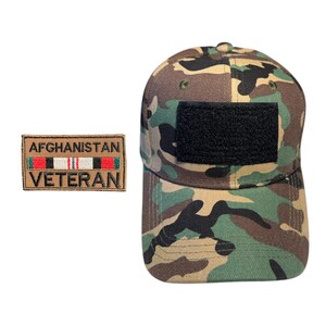 May include: Camouflage baseball cap with a black patch and an "AFGHANISTAN VETERAN" patch. The cap features a woodland camouflage pattern in shades of green, brown, and black. The rectangular patch has the text "AFGHANISTAN VETERAN" with a red, white, and green ribbon.
