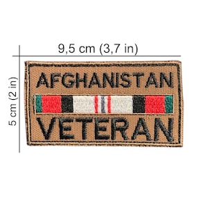 May include: A rectangular tan embroidered patch with black text reading AFGHANISTAN VETERAN. A horizontal ribbon graphic with red, black, white, and green stripes sits between the words. The patch measures 3.7 inches by 2 inches.
