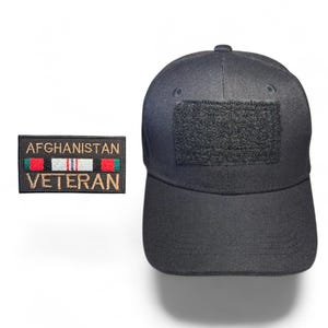 May include: Black baseball cap with a hook and loop patch and an embroidered patch. The embroidered patch reads "AFGHANISTAN VETERAN" with red, white, and green accents. The cap has a curved brim and a textured surface.