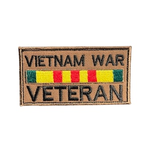 May include: A rectangular patch with the words "VIETNAM WAR VETERAN" in black lettering. The patch has a brown background and a horizontal stripe with green, yellow, and red segments.
