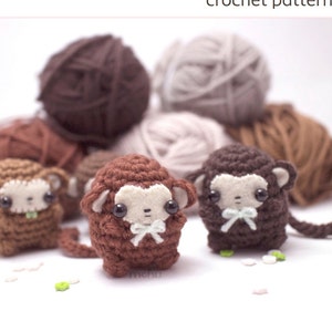 Könnte beinhalten: Ein Häkelmuster-Cover mit dem Text "little monkey amigurumi". Das Bild zeigt mehrere kleine, braune gehäkelte Affenfiguren mit weißen Gesichtern und Schleifen, zusammen mit Wollknäueln in verschiedenen Braun- und Beigetönen.