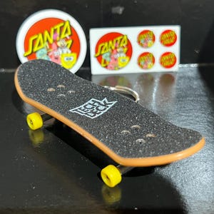 May include: A white ceramic mug with a black handle and the text "But First, Coffee" in a black, bold font. The mug is likely 325 ml in size and sits on a white surface.