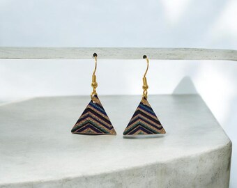 May include: A pair of gold triangle earrings with a blue and black geometric pattern. The earrings have a gold hook closure.