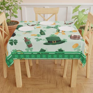 May include: A light green tablecloth featuring St. Patrick's Day motifs. The design includes green shamrocks, a green hat, a beer mug, a bottle of beer, and gold coins. The tablecloth is on a wooden table with four chairs.