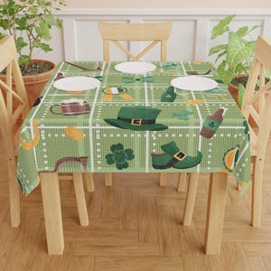 Może przedstawiać: Zielono-biały obrus w kratę z ilustracjami w tematyce Dnia Świętego Patryka. Projekt zawiera zielony kapelusz, koniczyny, piwo i buty. Obrus leży na drewnianym stole z białymi talerzami.