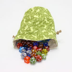 May include: A green drawstring dice bag with a light green woodland pattern, filled with a variety of colourful polyhedral dice. The dice are spilling out of the bag, showcasing different colours and numbers.
