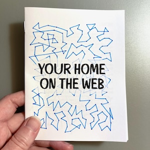 May include: A white booklet with blue line art and the text "YOUR HOME ON THE WEB" in black. The blue lines form an abstract pattern across the top of the booklet.