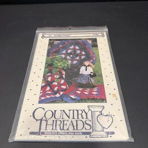 May include: A Country Threads sewing pattern packet titled 30-Something #156. The cover features a photograph of a doll wearing a white shirt and plaid skirt, surrounded by blue, red, and white patchwork quilts. The text includes the company name.