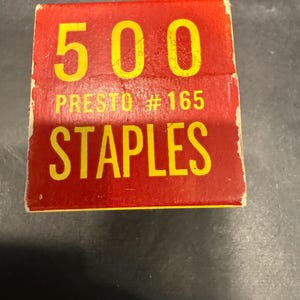 May include: A rectangular box of Presto #165 staples with a red background and yellow text. The box displays the number 500 at the top, followed by the text PRESTO #165 and the word STAPLES in large, bold, yellow capital letters.
