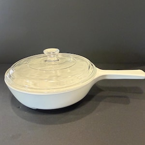 May include: A white ceramic mug with a black handle and the text "But First, Coffee" in a bold, black font. The mug is set against a blurred background, highlighting its clean design.