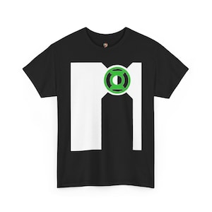 Può includere: Una t-shirt nera a maniche corte con una grande grafica rettangolare bianca sul petto. Al centro della parte superiore della grafica bianca si trova un emblema circolare verde e nero con il logo di Green Lantern e il suo simbolo.