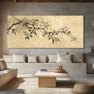 May include: A large rectangular canvas art piece featuring a branch with leaves in shades of black and gray against a beige background. The artwork is displayed above a modern sofa in a living room setting.