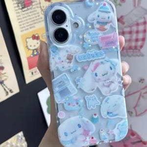 May include: Clear phone case decorated with blue and white cartoon characters and Japanese text. The case features various shapes and designs, including stars, clouds, and desserts. The case is designed to fit a smartphone.