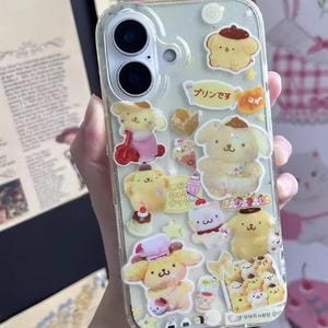 May include: Clear phone case decorated with yellow cartoon characters and Japanese text. The case has a clear background with multiple stickers of a dog-like character in various poses. The case is designed for a smartphone.