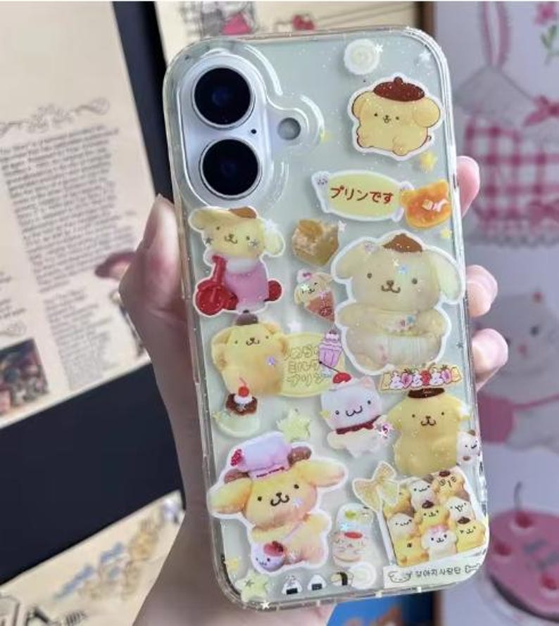 May include: Clear phone case decorated with yellow cartoon characters and Japanese text. The case has a clear background with multiple stickers of a dog-like character in various poses. The case is designed for a smartphone.