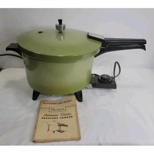 Puede incluir: Una olla a presión eléctrica vintage de color verde aguacate con mango y pomo de tapa negros. La olla cuenta con un cable de alimentación extraíble y un dial de control. Incluye un manual beige titulado Sears Automatic Electric Pressure Cooker.