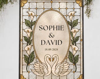 Puede incluir: Un letrero de boda rectangular con diseño de vidriera que presenta un óvalo central con el texto SOPHIE & DAVID y la fecha 18.09.2028. Dos cisnes blancos se miran bajo el texto, flanqueados por flores de cala y hojas verdes.