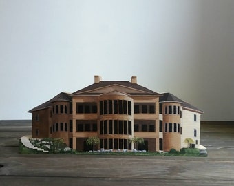 May include: A detailed model of a three-story house with a brown exterior and white trim. The house has multiple windows and a front porch. The model is made of wood and is painted to look realistic.