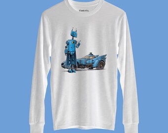 Può includere: Una maglietta bianca a maniche lunghe con una stampa grafica di un robot blu in piedi accanto a un'auto sportiva blu. Il robot fa il segno di pace con la mano. Il testo "Clank n Co." è stampato in nero all'interno della zona del colletto.