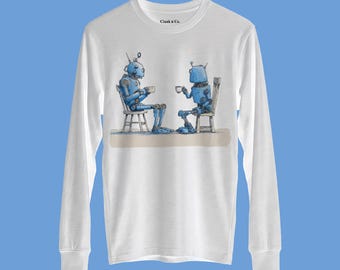 Può includere: Una maglietta bianca a maniche lunghe con un'illustrazione grafica di due robot blu seduti su sedie che bevono da tazze. Il testo Clank n Co. è stampato in nero vicino allo scollo. Il disegno è centrato sulla parte anteriore del capo.