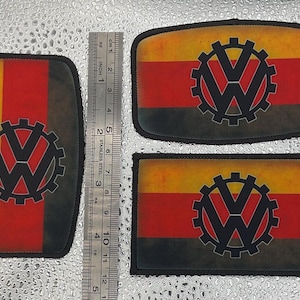 May include: Three patches with a distressed design featuring the Volkswagen logo within a gear. The patches have a black border and a color scheme of yellow, red, and black. The patches are approximately 2 to 4 inches in length.