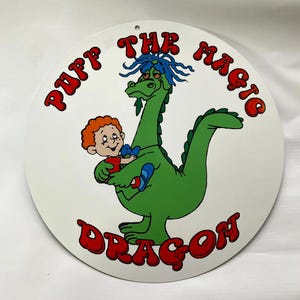 Pu&ograve; includere: Cartello rotondo bianco con un'illustrazione a cartoni animati di un drago verde con i capelli blu che tiene in braccio un bambino. Il cartello riporta le parole "Puff The Magic Dragon" in lettere rosse sul bordo.