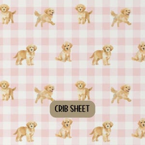 May include: Crib sheet with a repeating pattern of golden retriever puppies on a pink and white gingham background. The text "CRIB SHEET" is displayed on a tan rectangle.