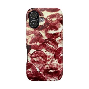 May include: A phone case featuring a pattern of red lipstick kiss marks on a cream-colored background. The case has a glossy finish and a black border, with camera cutouts visible at the top.
