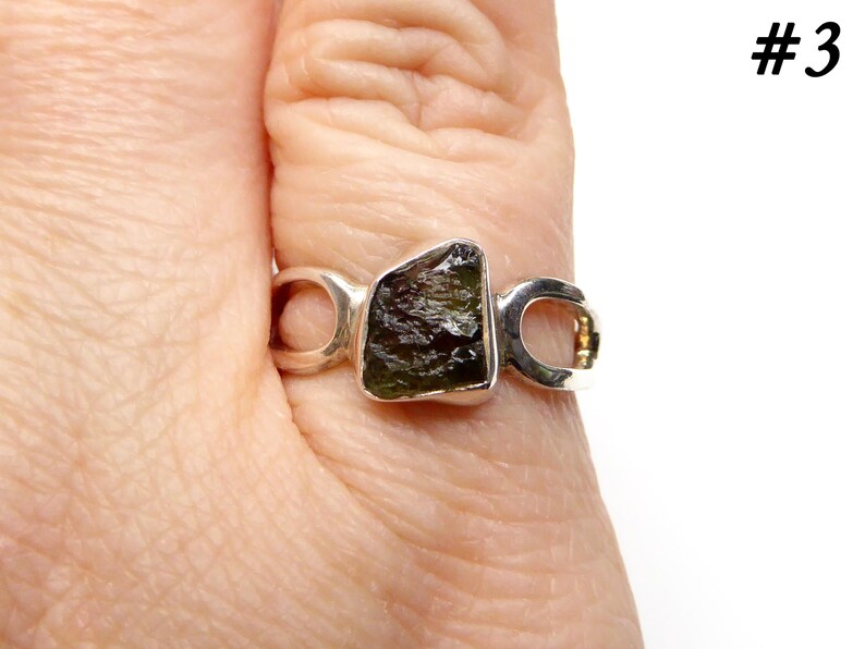 May include: A silver ring with a green and black gemstone set in a unique open design. #3