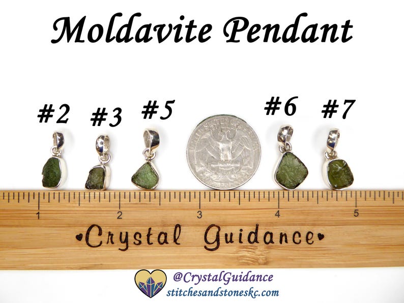 May include: Five silver pendants with green moldavite stones, numbered 2, 3, 5, 6, and 7. The pendants are arranged in a row on a wooden ruler with a "Crystal Guidance" logo.