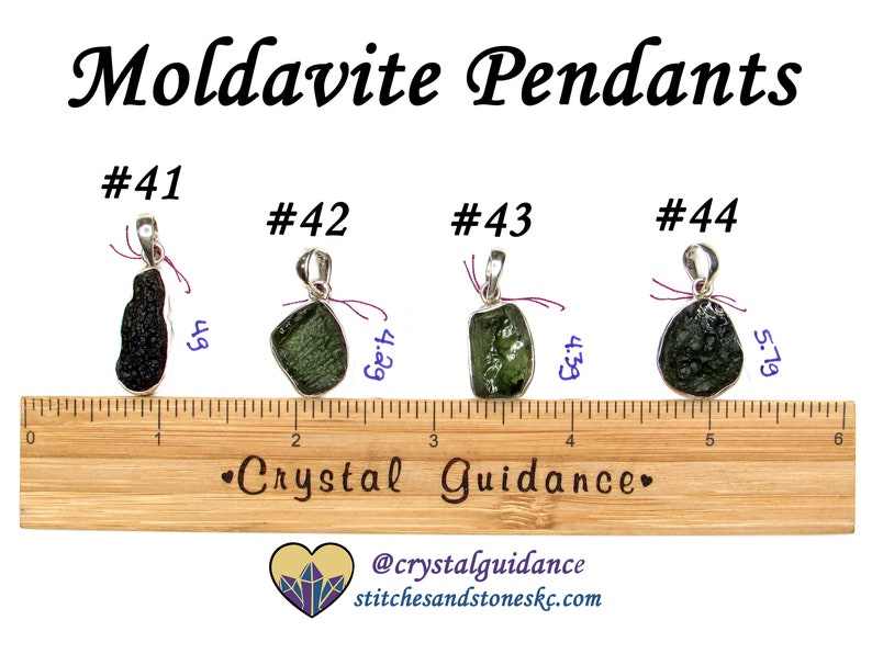 May include: Four Moldavite pendants with silver bail settings. The pendants are displayed on a wooden ruler with measurements in inches. The pendants are numbered #41, #42, #43, and #44. The text "Crystal Guidance" is printed on the ruler. The text "@crystalguidance stitchesandstoneskc.com" is printed below the ruler.