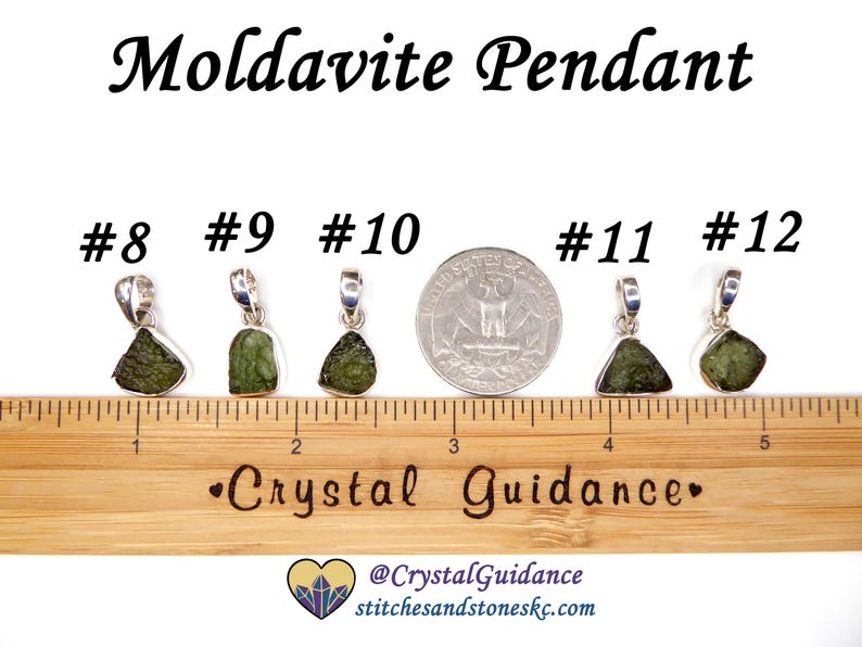 May include: Five silver pendants with green moldavite stones, numbered 8 through 12, are lined up on a wooden ruler with a "Crystal Guidance" logo. The ruler is marked in inches.
