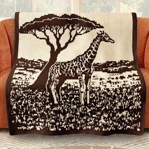 Puede incluir: Una manta beige y marrón con un diseño pixelado de una jirafa y un árbol en una sabana. La manta está sobre un sofá naranja, agregando un toque decorativo a la habitación.