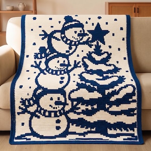 May include: A rectangular crochet blanket featuring a cream-colored base with a dark blue pixelated pattern. The design depicts three stacked snowmen next to a Christmas tree topped with a star, surrounded by small square snowflakes throughout.